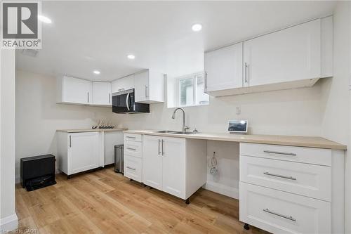 Kitchen with white cabinets, light wood-style flooring, light countertops, stainless steel microwave, and recessed lighting - 699 Frederick Street, Kitchener, ON - Indoor Photo Showing Kitchen With Double Sink