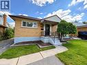 Brick exterior featuring a covered entry, concrete steps with metal railings, a paved driveway, and a front yard with grass and mature landscaping - 699 Frederick Street, Kitchener, ON 