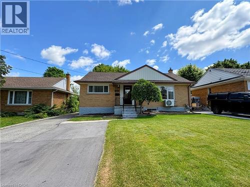Traditional brick exterior with a pitched shingle roof, featuring a front porch with steps and a manicured lawn - 699 Frederick Street, Kitchener, ON 