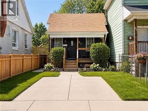Front exterior featuring a covered porch, wood plank steps, and a dark-toned entry door - 67 Glendale Avenue N, Hamilton, ON - Outdoor