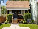 Charming exterior featuring a covered porch with wooden steps, dark-painted siding, and a light brown roof - 67 Glendale Avenue N, Hamilton, ON  - Outdoor 