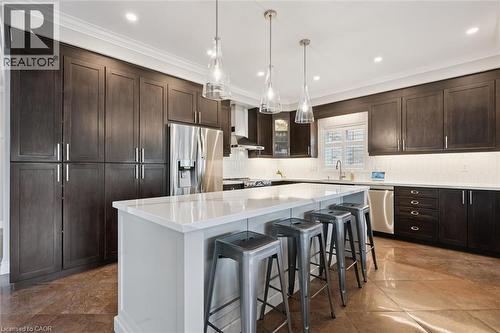 Kitchen featuring dark wood finish cabinetry, a breakfast bar area, stainless steel appliances, a center island, and crown molding - 469 Woodbine Avenue, Kitchener, ON - Indoor Photo Showing Kitchen With Stainless Steel Kitchen With Upgraded Kitchen
