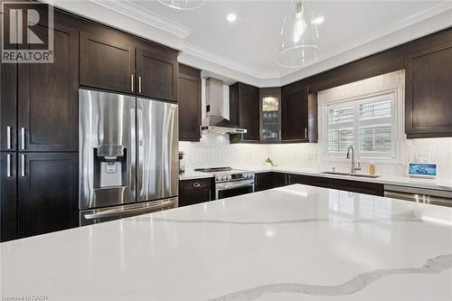 Kitchen featuring stainless steel appliances, glass fronted cabinets, light stone counters, dark wood finish cabinets, and ornamental molding - 469 Woodbine Avenue, Kitchener, ON - Indoor Photo Showing Kitchen With Stainless Steel Kitchen With Upgraded Kitchen
