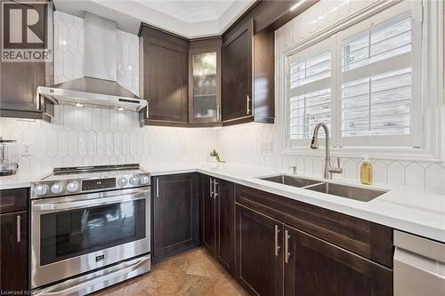 Kitchen featuring stainless steel appliances, dark wood finish cabinetry, decorative backsplash, glass fronted cabinets, and light stone countertops - 469 Woodbine Avenue, Kitchener, ON - Indoor Photo Showing Kitchen With Double Sink With Upgraded Kitchen