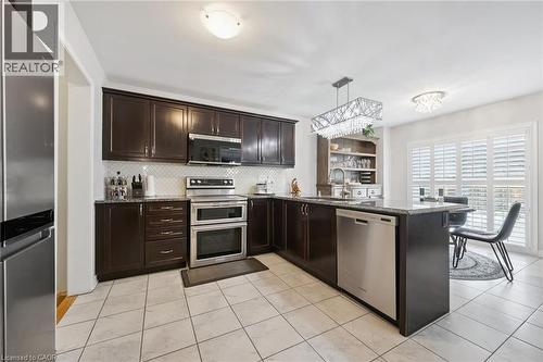 Kitchen featuring a peninsula, dark wood finish cabinets, stainless steel appliances, dark stone counters, and pendant lighting - 38 Park Glen Street, Kitchener, ON - Indoor Photo Showing Kitchen With Stainless Steel Kitchen With Upgraded Kitchen