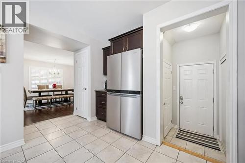 Kitchen with dark wood finish cabinets, freestanding refrigerator, light tile patterned floors, and hanging lights - 38 Park Glen Street, Kitchener, ON - Indoor