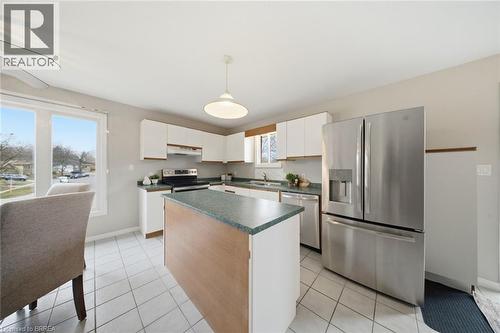 Kitchen featuring stainless steel appliances, a kitchen island, white cabinets, decorative light fixtures, and dark countertops - 7 Forest Drive, Paris, ON - Indoor Photo Showing Kitchen
