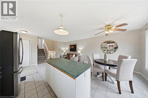 Kitchen featuring freestanding refrigerator, white cabinets, dark countertops, hanging light fixtures, and light tile patterned floors - 7 Forest Drive, Paris, ON - Indoor Photo Showing Dining Room