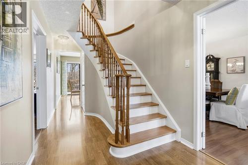 Staircase with a textured ceiling, a chandelier, and wood finished floors - 18 Webster Way, Georgetown, ON - Indoor Photo Showing Other Room