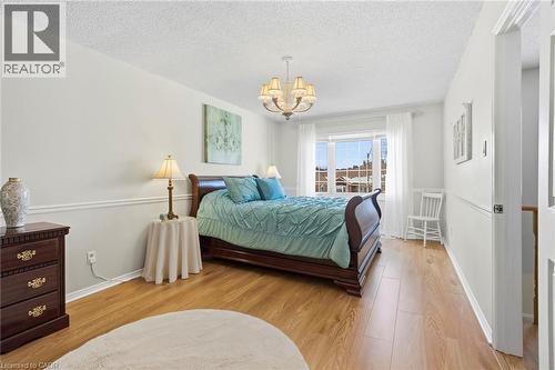 Bedroom featuring light wood-style floors, suspended lighting, and a textured ceiling - 18 Webster Way, Georgetown, ON - Indoor Photo Showing Bedroom