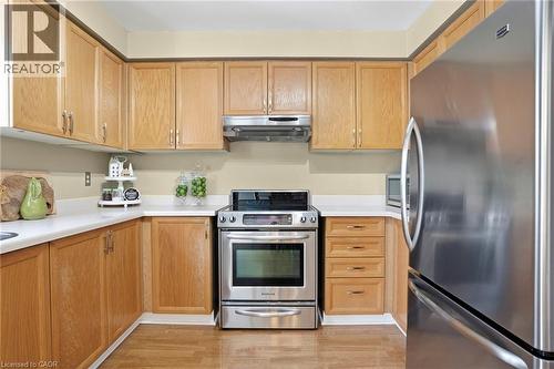 Kitchen with stainless steel appliances, light countertops, and light wood finished floors - 18 Webster Way, Georgetown, ON - Indoor Photo Showing Kitchen