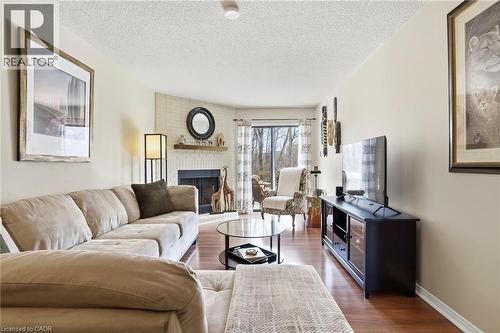 Living area featuring wood finished floors, a brick fireplace, and a textured ceiling - 18 Webster Way, Georgetown, ON - Indoor Photo Showing Living Room With Fireplace