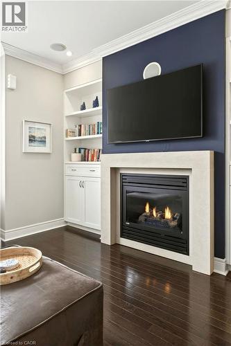 Living area featuring ornamental molding, dark wood-style floors, a glass covered fireplace, and built in features - 1862 Burnhamthorpe Road, Mississauga, ON - Indoor Photo Showing Living Room With Fireplace