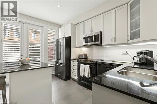 Kitchen with dark stone counters, black appliances, white cabinets, and recessed lighting - 1862 Burnhamthorpe Road, Mississauga, ON - Indoor Photo Showing Kitchen With Double Sink