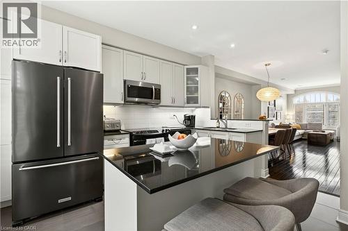 Kitchen with stainless steel appliances, glass fronted cabinets, a center island, white cabinets, and pendant lighting - 1862 Burnhamthorpe Road, Mississauga, ON - Indoor Photo Showing Kitchen With Upgraded Kitchen