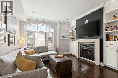 Living area featuring crown molding, built in shelves, a glass covered fireplace, and dark wood-style flooring - 1862 Burnhamthorpe Road, Mississauga, ON - Indoor Photo Showing Living Room With Fireplace