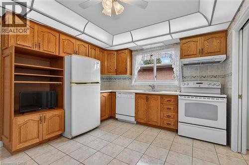 Kitchen featuring white appliances, wood finish cabinetry, ceiling fan, light countertops, and light tile patterned flooring - 21 Bluebird Avenue, Hamilton, ON 