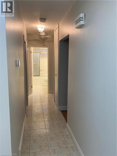 Hallway with square tile flooring, light-toned walls, and white trim - 21 Bluebird Avenue, Hamilton, ON 