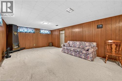 Living area with carpet flooring and wooden walls - 21 Bluebird Avenue, Hamilton, ON 