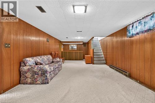 Living area featuring a baseboard radiator, wooden walls, and light carpet - 21 Bluebird Avenue, Hamilton, ON 