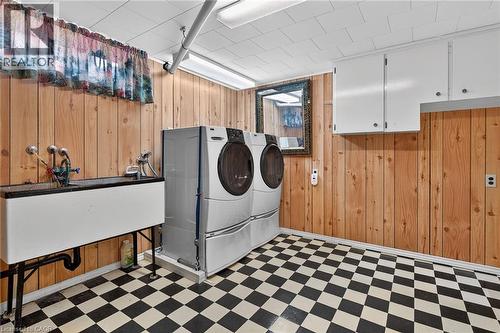 Laundry area featuring light flooring, wooden walls, and washing machine and clothes dryer - 21 Bluebird Avenue, Hamilton, ON 