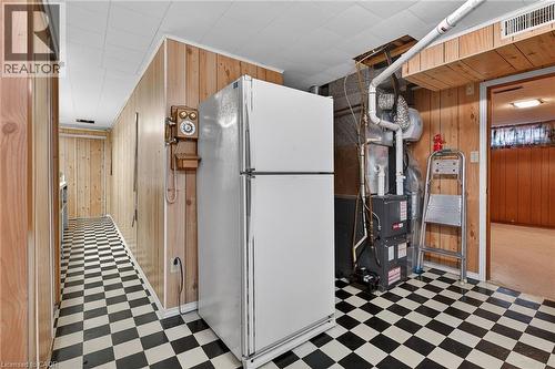 Kitchen with wooden walls, light flooring, freestanding refrigerator, and heating unit - 21 Bluebird Avenue, Hamilton, ON 