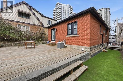 Back of house with a chimney, a deck, brick siding, entry steps, and a yard - 129 Jackson Street W, Hamilton, ON - Outdoor With Exterior