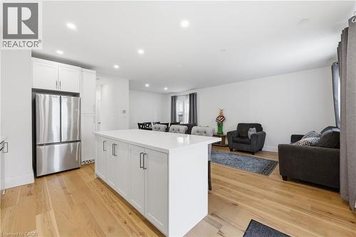 Kitchen with open floor plan, freestanding refrigerator, a kitchen island, light wood-style flooring, and white cabinetry - 129 Jackson Street W, Hamilton, ON - Indoor Photo Showing Kitchen