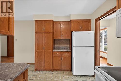 Kitchen featuring wood finish cabinets, white appliances, backsplash, and light stone counters - 122 Glen Forest Drive, Hamilton, ON - Indoor Photo Showing Kitchen