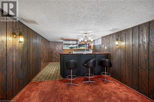 Indoor dry bar featuring dark colored carpet, a textured ceiling, and wooden walls - 122 Glen Forest Drive, Hamilton, ON - Indoor Photo Showing Other Room