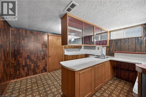 Kitchen featuring a peninsula, dark floors, wood walls, light countertops, and wood finish cabinetry - 122 Glen Forest Drive, Hamilton, ON - Indoor