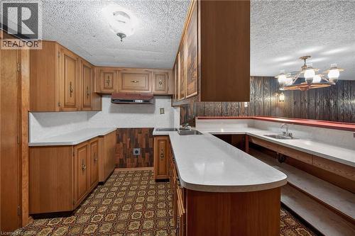 Kitchen with wooden walls, dark floors, wood finish cabinets, light countertops, and a textured ceiling - 122 Glen Forest Drive, Hamilton, ON - Indoor Photo Showing Kitchen