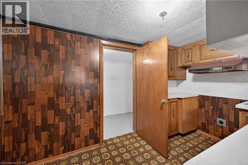 Kitchen with dark flooring, wood finish cabinetry, wood walls, and light countertops - 122 Glen Forest Drive, Hamilton, ON - Indoor