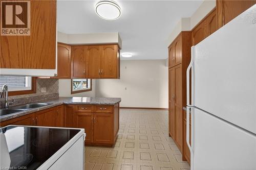 Kitchen with freestanding refrigerator, light flooring, range with electric stovetop, wood finish cabinets, and a peninsula - 122 Glen Forest Drive, Hamilton, ON - Indoor Photo Showing Kitchen With Double Sink