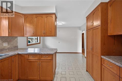Kitchen with a peninsula, wood finish cabinets, light floors, and tasteful backsplash - 122 Glen Forest Drive, Hamilton, ON - Indoor Photo Showing Kitchen