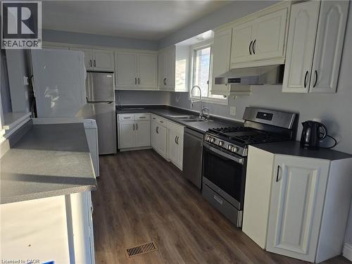 Kitchen featuring stainless steel appliances, white cabinets, dark countertops, and exhaust hood - 593 Mount Anne Drive, Waterloo, ON - Indoor Photo Showing Kitchen With Double Sink
