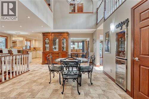 Dining space featuring light stone finish flooring, a high ceiling, beverage cooler, and a chandelier - 15 Marquette Drive, Kitchener, ON - Indoor Photo Showing Dining Room