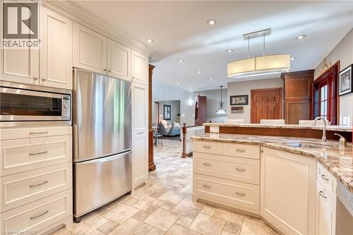 Kitchen with stainless steel appliances, light stone counters, pendant lighting, cream cabinets, and stone finish flooring - 15 Marquette Drive, Kitchener, ON - Indoor Photo Showing Kitchen