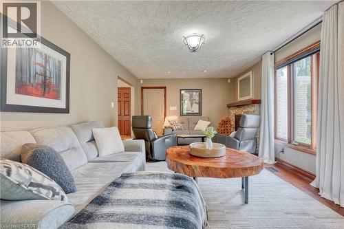 Living room featuring wood finished floors, a textured ceiling, and a fireplace - 15 Marquette Drive, Kitchener, ON - Indoor