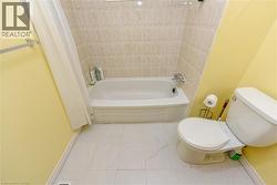 Bathroom featuring toilet and shower / tub combo with curtain - 