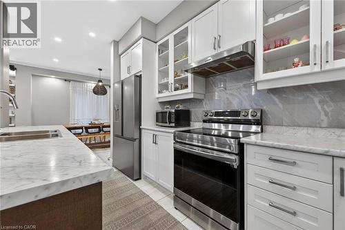 Kitchen with stainless steel appliances, glass insert cabinets, white cabinets, decorative backsplash, and decorative light fixtures - 7809 Hackberry Trail E, Niagara Falls, ON - Indoor Photo Showing Kitchen With Double Sink With Upgraded Kitchen