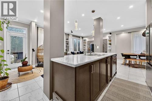Kitchen with dark wood finish cabinetry, pendant lighting, open floor plan, a kitchen island with sink, and stainless steel fridge - 7809 Hackberry Trail E, Niagara Falls, ON - Indoor Photo Showing Kitchen With Upgraded Kitchen