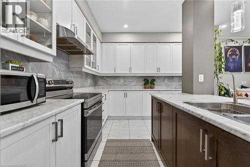 Kitchen with stainless steel appliances, glass insert cabinets, two tone cabinets, exhaust hood, and decorative backsplash - 7809 Hackberry Trail E, Niagara Falls, ON - Indoor Photo Showing Kitchen With Upgraded Kitchen