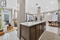 Kitchen with dark wood finish cabinetry, pendant lighting, open floor plan, a kitchen island with sink, and stainless steel fridge - 