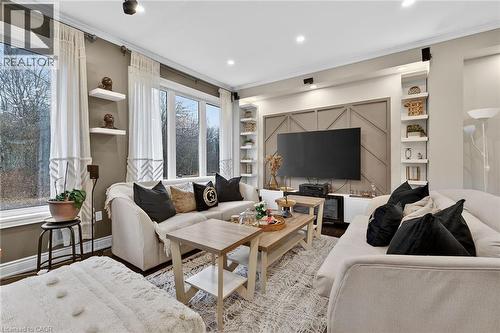 Living room with built in shelves, wood finished floors, ornamental molding, and recessed lighting - 7809 Hackberry Trail E, Niagara Falls, ON - Indoor Photo Showing Living Room