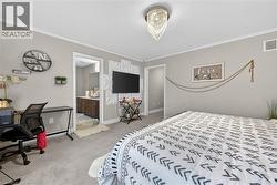 Bedroom featuring a desk, light carpet, ornamental molding, and connected bathroom - 