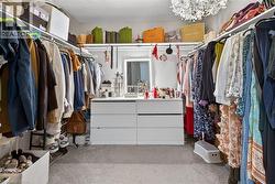Walk in closet with light colored carpet and hanging lights - 