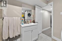 Bathroom featuring light tile patterned flooring, vanity, and stacked washer and clothes dryer - 