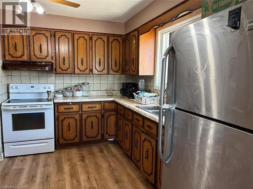 Kitchen with freestanding refrigerator, light countertops, white electric range oven, a ceiling fan, and light wood-style floors - 1224 Dunsmure Road, Hamilton, ON - Indoor Photo Showing Kitchen With Double Sink