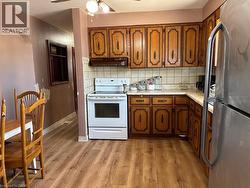 Kitchen with light countertops, arched walkways, freestanding refrigerator, electric range, and tasteful backsplash - 